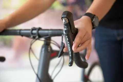 Hand op het schakelen van een racefiets, met de Ultegra-aanduiding zichtbaar op de remhendel.