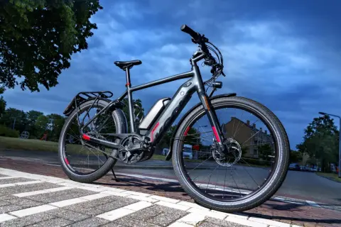 Grijze speed pedelec met bagagedrager en accu, klaar voor een rit. Het kenteken is niet zichtbaar, maar de fiets is wel voorzien van alle benodigde onderdelen.