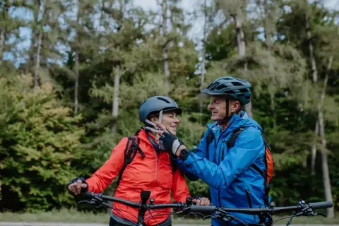 Een stel op mountainbikes, met fietshelm verplicht in Frankrijk, geniet van een bosrit.