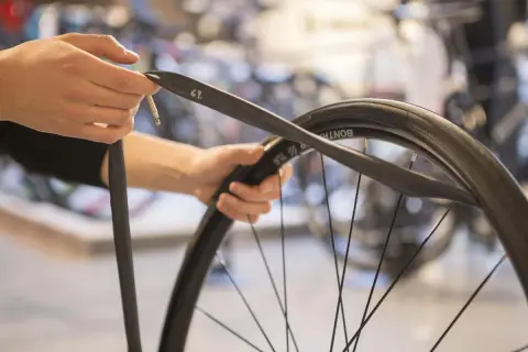 Handen monteren een nieuwe binnenband op een fietswiel.