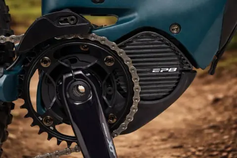 Close-up van een e-bike aandrijfsysteem met Shimano STEPS motor. De ketting loopt over de tandwielen en de motorbehuizing met EP8-logo.