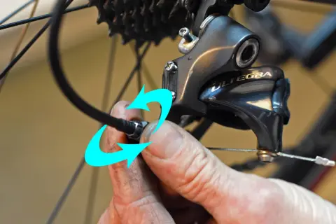 Hand probeert de kabel van de derailleur te bevestigen, maar het derailleur afstellen lukt niet.
