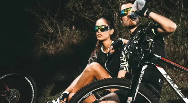 Een stel geniet van een pauze tijdens hun eerste mountainbike avontuur. Ze zitten naast hun fietsen, met de zon op hun gezichten.