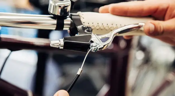 Hand replacing a bicycle's remkabel. Close-up of the brake lever and cable connection.