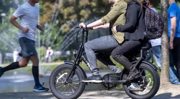 Een stel rijdt op een fatbike, terwijl een hardloper ernaast rent. Nadelen fatbike: minder beweging, meer overlast.