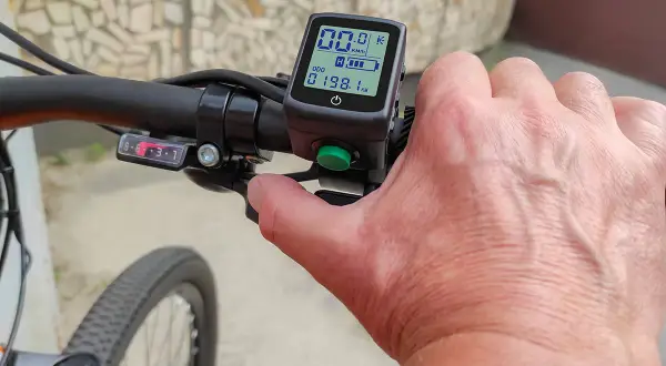 Hand op stuur van een elektrische fiets zonder trappen. Het display toont 00.0 km/u en 198.1 km.