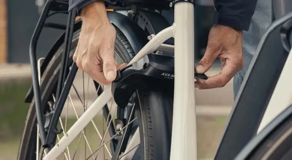 Een persoon bevestigt een ringslot aan een fiets. Dit type slot, wat is een ringslot, beschermt tegen diefstal door het achterwiel te blokkeren.