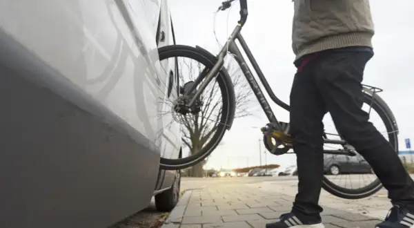 Man met fiets bij auto. Een diefstal preventie chip op de fiets zorgt voor extra veiligheid.