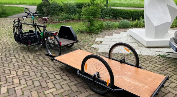 Een fiets met een bakfiets-achtige constructie en een aanhanger, klaar om een zijspan fiets te maken.