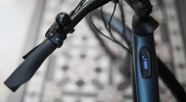 Stuur van een blauwe elektrische fiets met een display dat aangeeft dat de elektrische fiets slaat op hol. De batterij is vol.