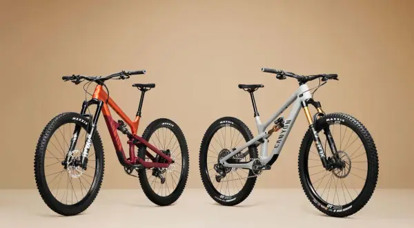 Twee mountainbikes, één oranje/rood en één grijs, met duidelijke wielmaat en Maxxis banden.