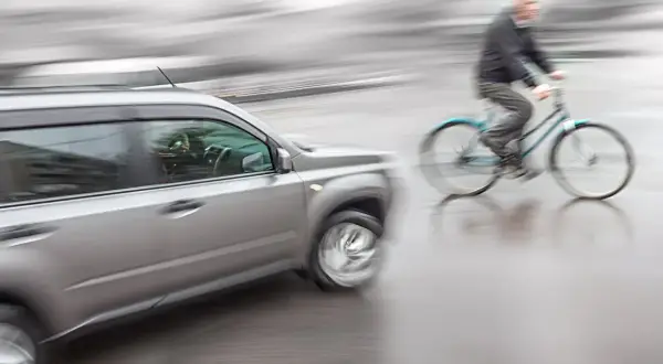 Een auto en fietser in beweging, mogelijk een situatie die leidt tot schadevergoeding fietsongeval.