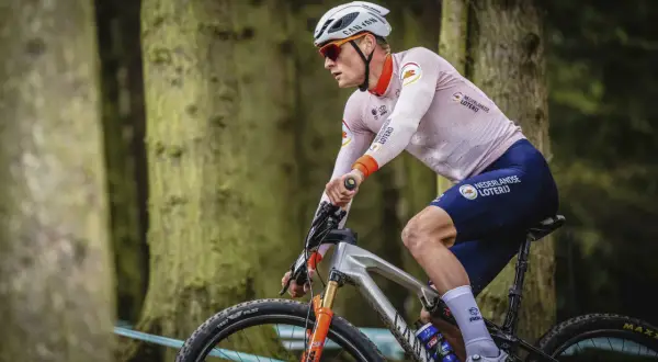Een Nederlandse wielrenner in actie in het bos, met de Nederlandse Loterij op zijn shirt.