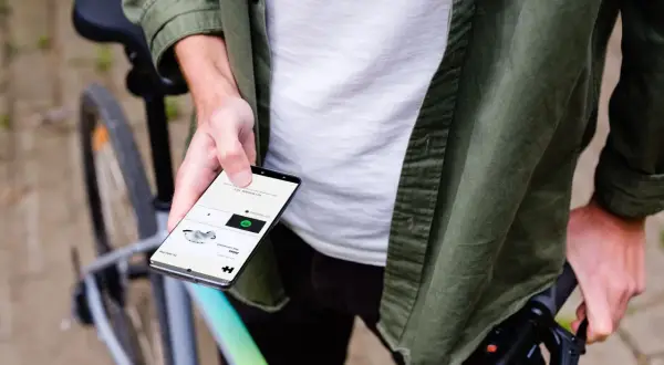 Man op fiets houdt smartphone vast, toont app voor communiceren tijdens fietsen.