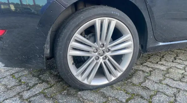 Een lekke band op de racefiets van de auto. De band is plat en de velg rust op de stenen ondergrond.