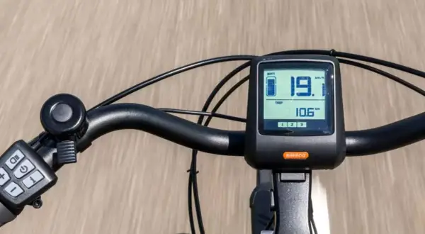 Close-up of an e-bike handlebar with a digital display showing speed and battery level.