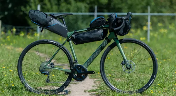 Groene Merida racefiets met bikepacking tassen, klaar voor een avontuurlijke tocht.