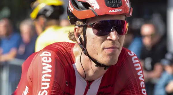 Een wielrenner in rood Sunweb-tenue, met helm en zonnebril, klaar voor de strijd. Bekende wielrenners zoals hij maken indruk.