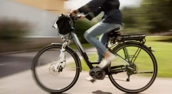 Een persoon op een elektrische fiets, die met gemak 30 km/u bereikt, fietst langs een groen park.