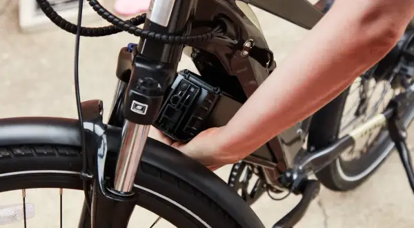Hand plaatst accu terug in elektrische fiets voor onderhoud.