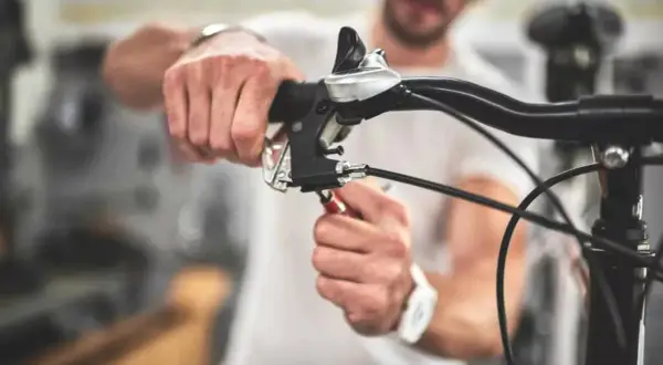 Man stelt de terugtraprem af met een sleutel aan het stuur van een fiets.