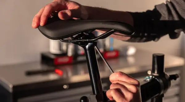 Handen die een fietszadel vervangen met een inbussleutel.
