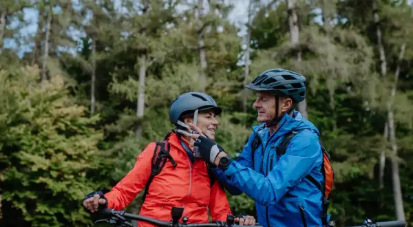 Een stel op mountainbikes, met fietshelm verplicht in Frankrijk, geniet van een bosrit.
