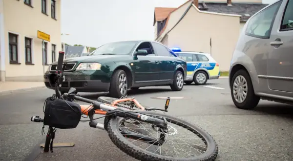 Een fiets ligt op straat na een aanrijding fiets met fiets. Politieauto's zijn ter plaatse.