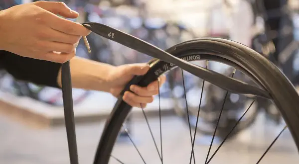 Handen monteren een nieuwe binnenband op een fietswiel.