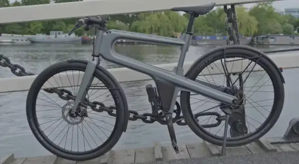 Moderne, hippe stadsfiets met een uniek frame, geparkeerd op een brug met uitzicht op boten.