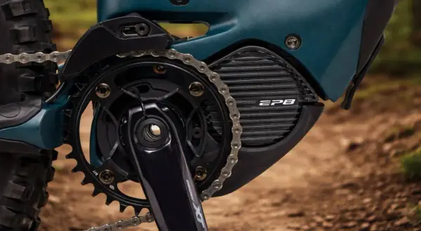 Close-up van een e-bike aandrijfsysteem met Shimano STEPS motor. De ketting loopt over de tandwielen en de motorbehuizing met EP8-logo.