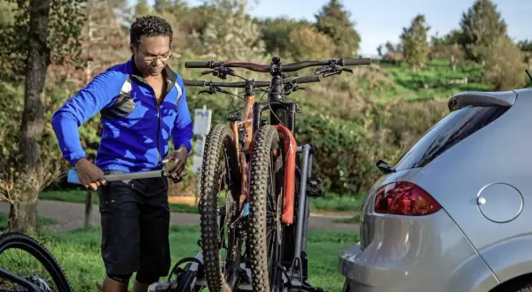 Man laadt fietsen op een fietsendrager achter een auto. Hopelijk is de fiets gestolen inboedelverzekering geregeld.