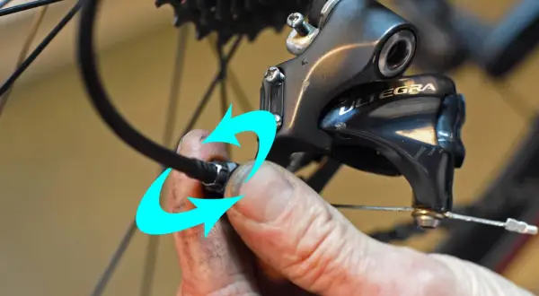 Hand probeert de kabel van de derailleur te bevestigen, maar het derailleur afstellen lukt niet.