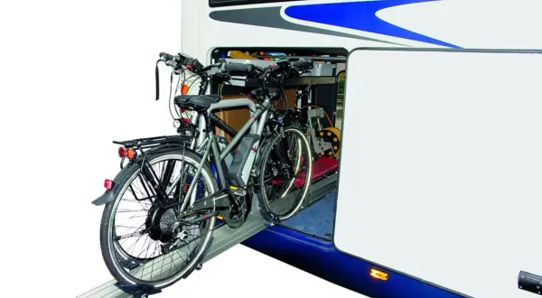 Twee elektrische fietsen staan klaar voor transport in de ruime schuur van een camper.