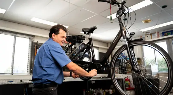 Man werkt aan een fiets, mogelijk om deze om te bouwen naar een driewieler.