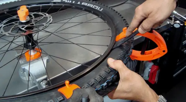 Fietsband monteren lukt niet. Een oranje bandenlichter helpt om de buitenband op de velg te krijgen.