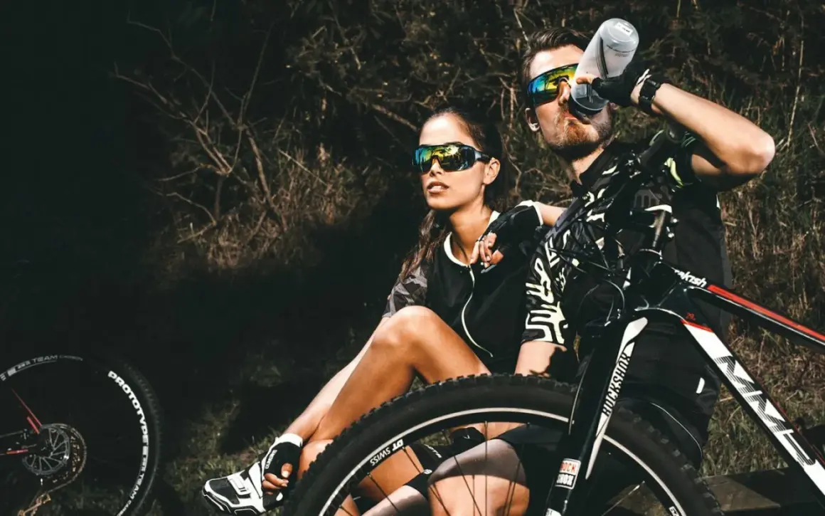 Een stel geniet van een pauze tijdens hun eerste mountainbike avontuur. Ze zitten naast hun fietsen, met de zon op hun gezichten.