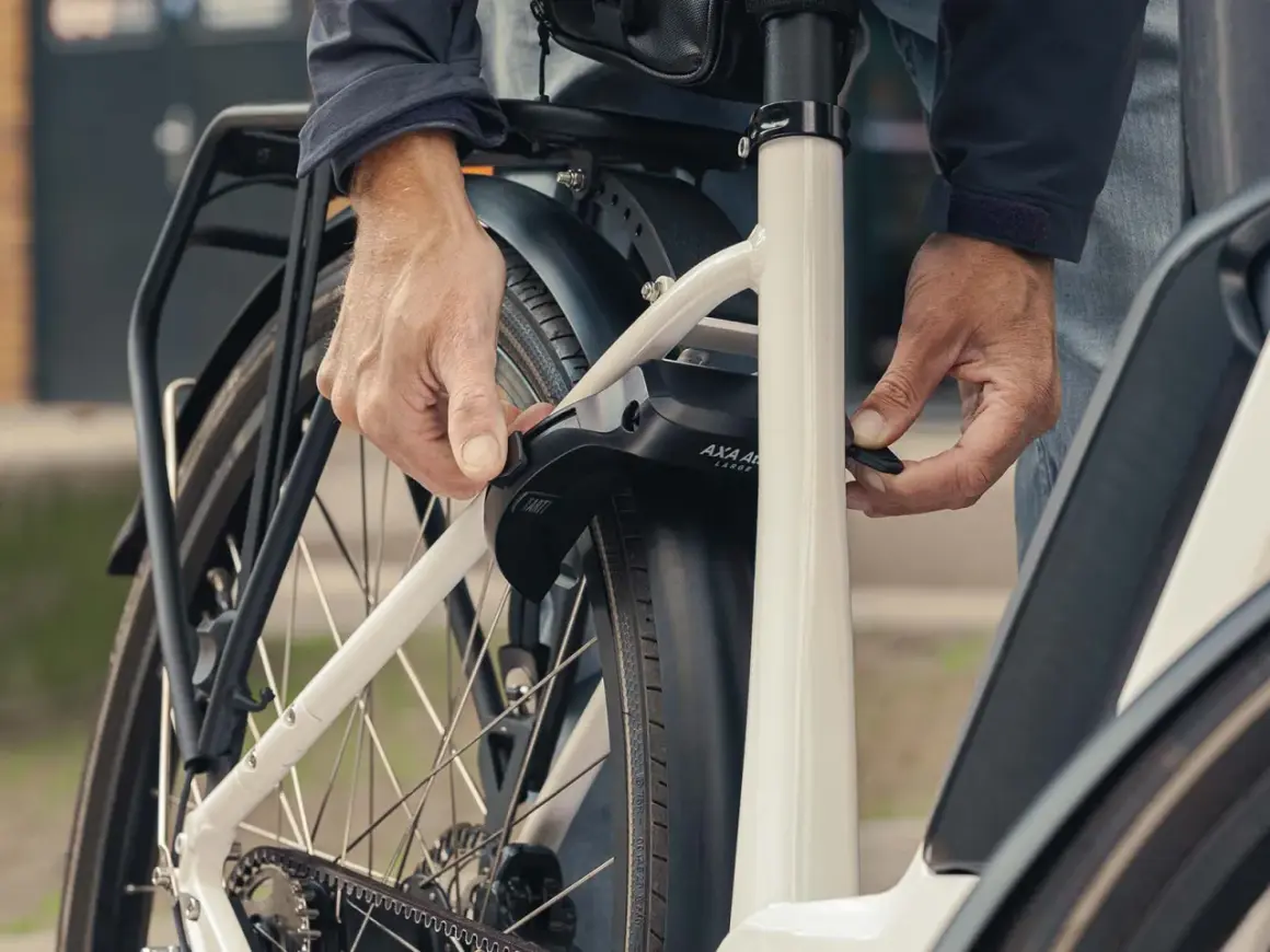 Een persoon bevestigt een ringslot aan een fiets. Dit type slot, wat is een ringslot, beschermt tegen diefstal door het achterwiel te blokkeren.