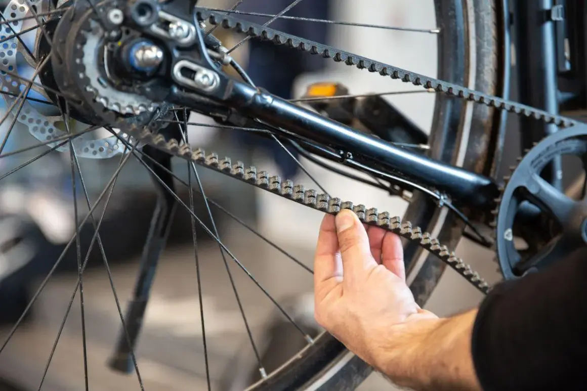 Hand controleert de riem van een fiets, mogelijk ter voorbereiding op het vervangen van de riem fiets.