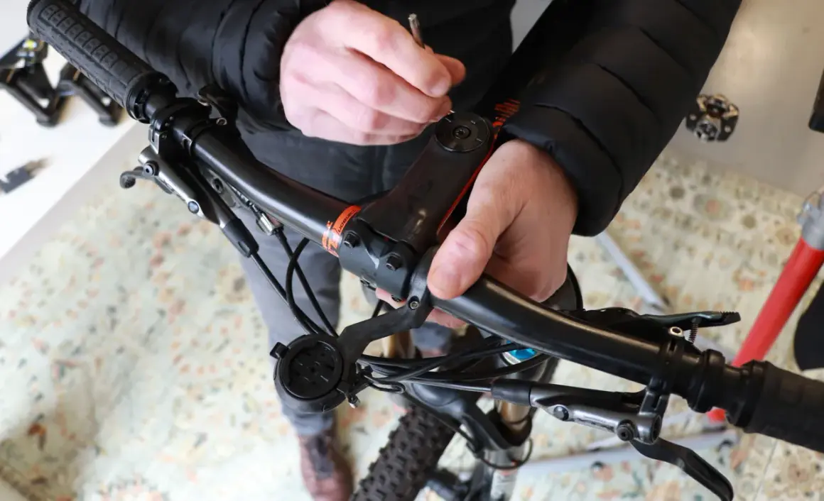 Handen stellen balhoofd fiets af met gereedschap. Zorg dat alles stevig vastzit voor een veilige rit.