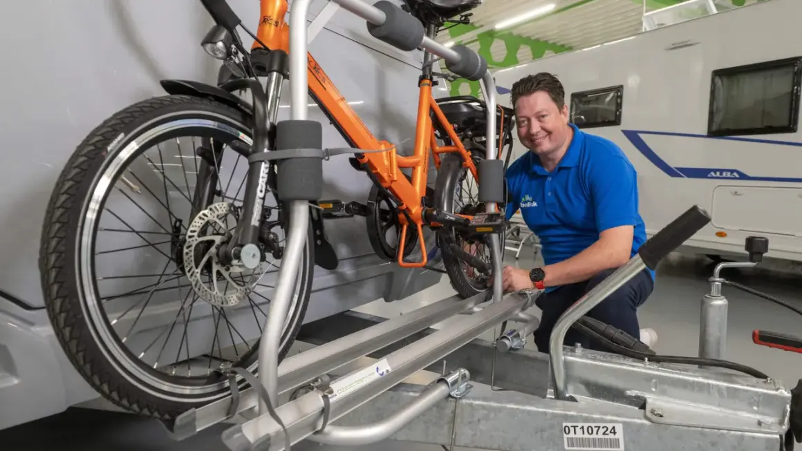 Man toont fietsendrager voor caravan, ideaal om een elektrische fiets veilig te vervoeren.