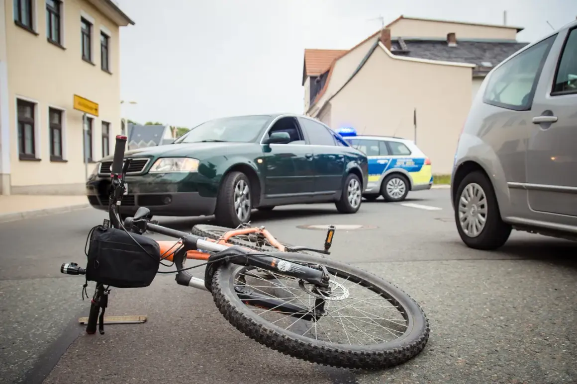 Een fiets ligt op straat na een aanrijding fiets met fiets. Politieauto's zijn ter plaatse.