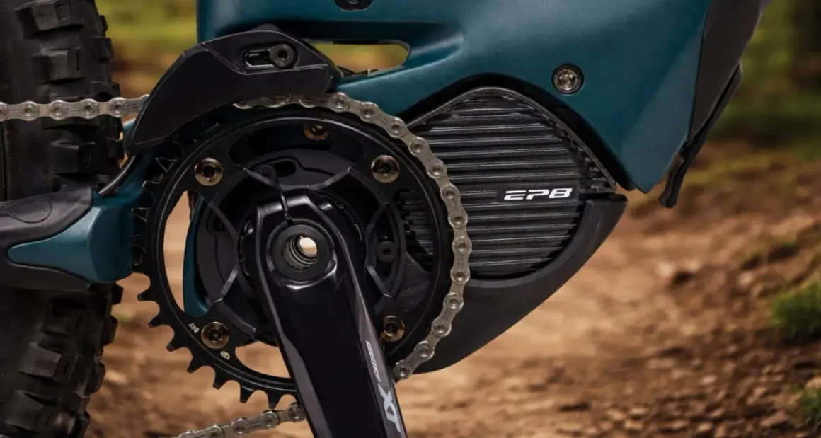 Close-up van een e-bike aandrijfsysteem met Shimano STEPS motor. De ketting loopt over de tandwielen en de motorbehuizing met EP8-logo.