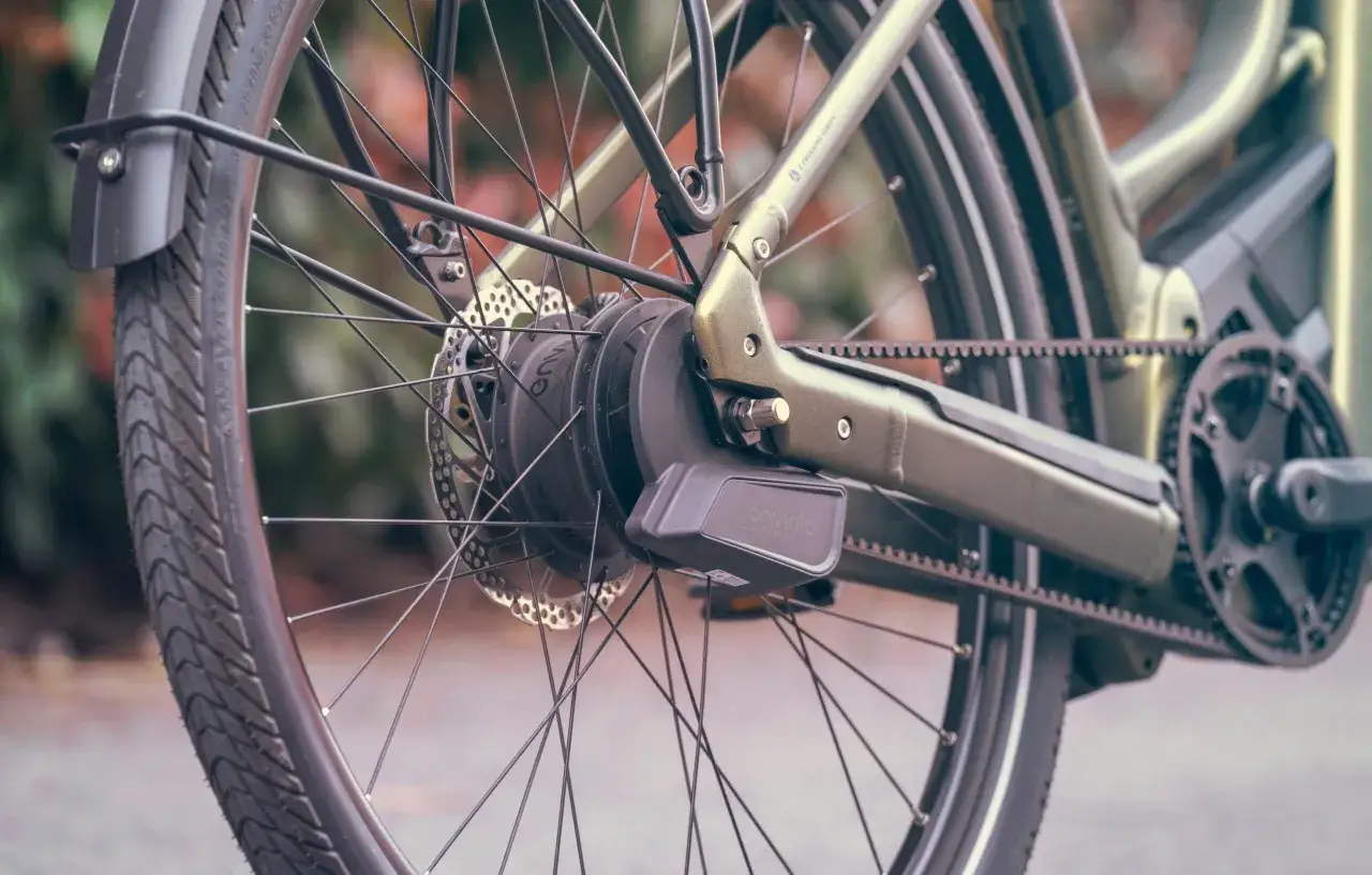 Close-up van een e-bike met een Enviolo traploze versnelling en een riemaandrijving. De schijfrem is zichtbaar.
