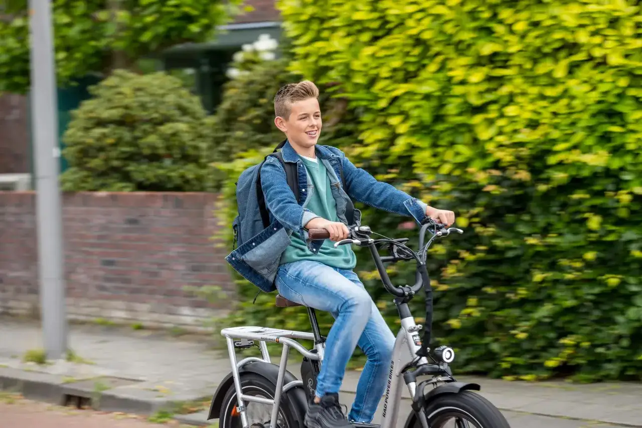 Jonge jongen op een fatbike, met rugzak, genietend van de rit. Nadelen fatbike: zwaar, duur, en kan overlast veroorzaken.