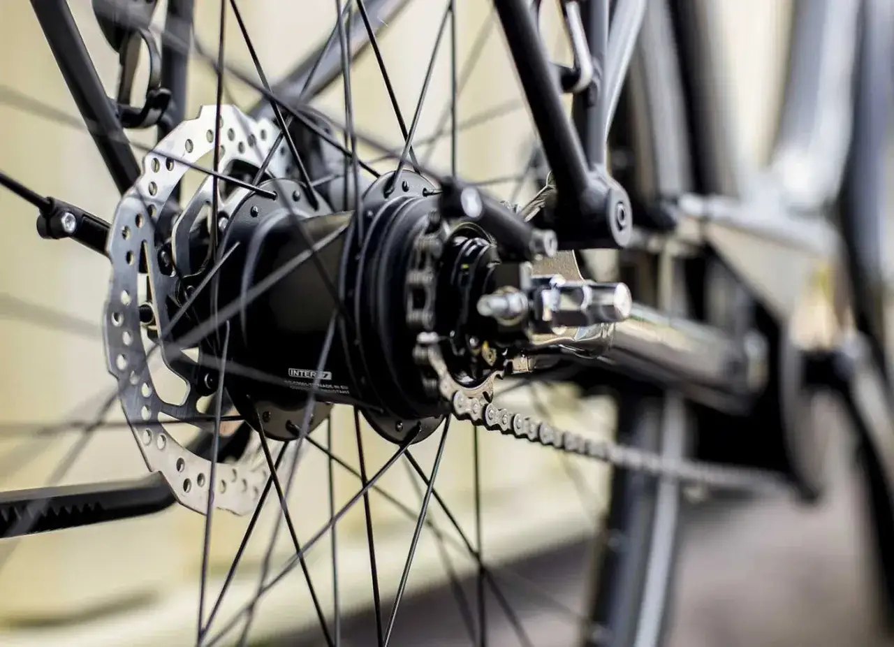 Close-up van een fietswiel met schijfrem en kettingaandrijving. Mogelijk zijn er pinion problemen met deze versnellingsnaaf.