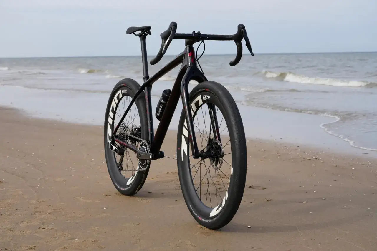Een zwarte racefiets met brede banden staat op het strand, klaar voor avontuurlijke beach bikes tochten langs de zee.