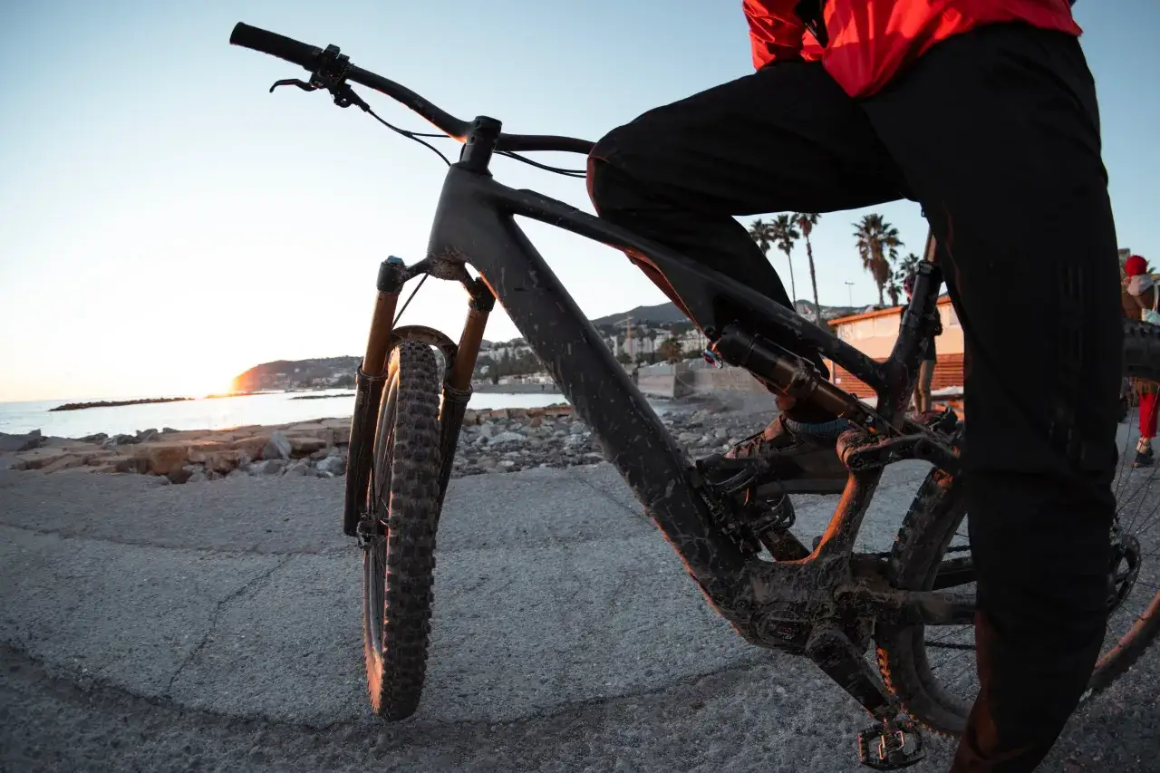 Een mountainbiker met een Cube framemaat, klaar voor een rit bij zonsondergang aan zee.
