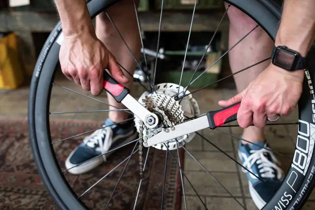 Handen gebruiken gereedschap om de cassette van een fietswiel te vervangen.