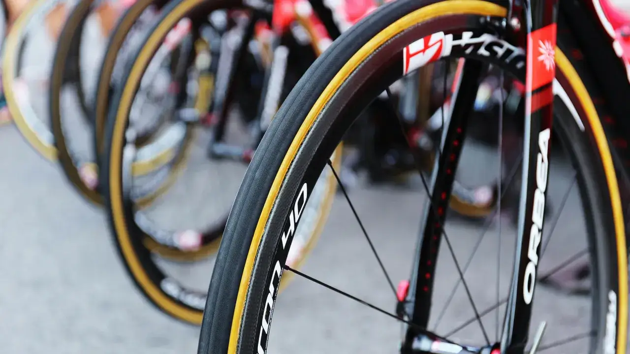 Close-up van racefietswielen, klaar voor de bandbreedte race van profs. De carbon velgen en gele banden glimmen.